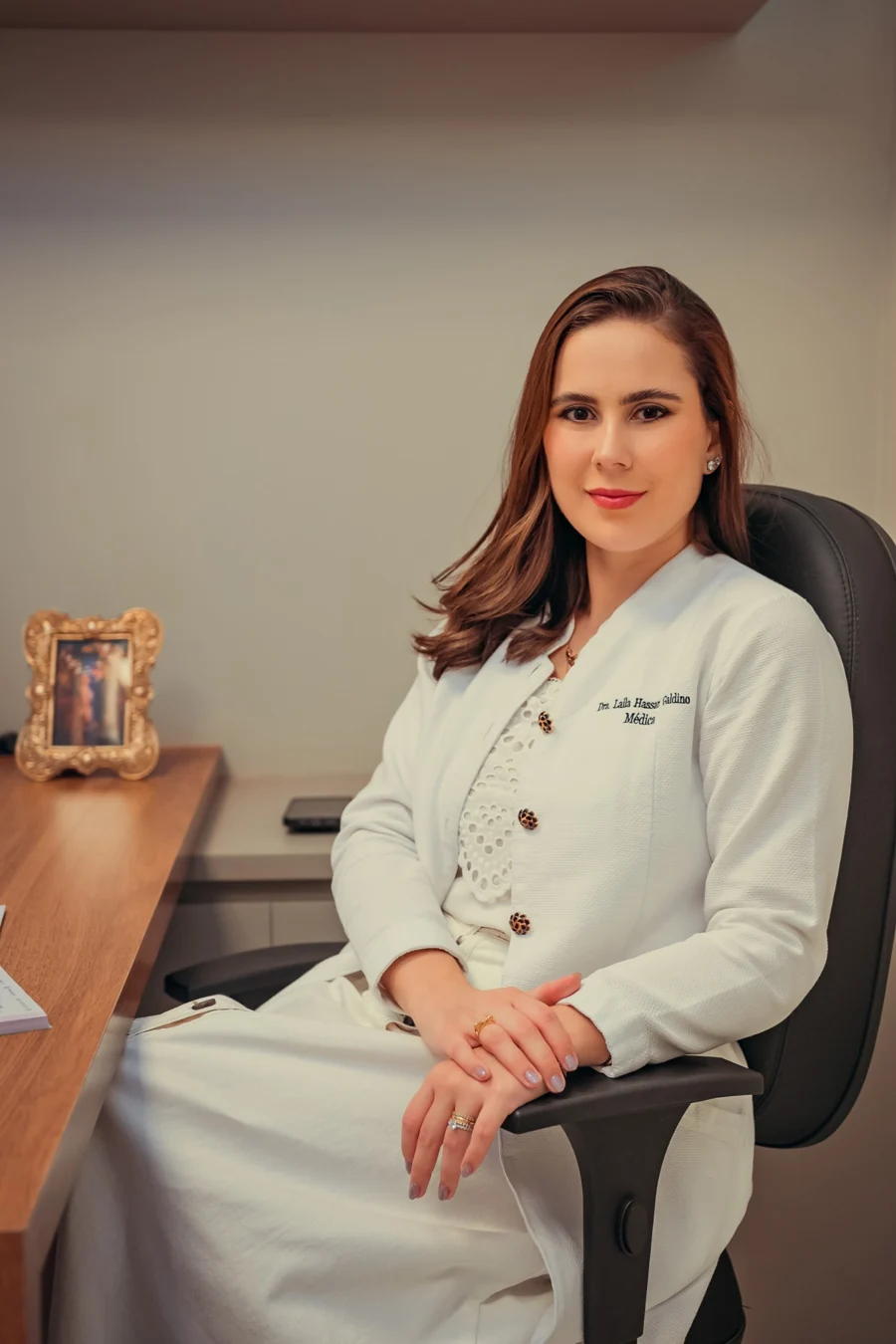 Dra. Laila Hassan sentada em seu consultório, com jaleco branco